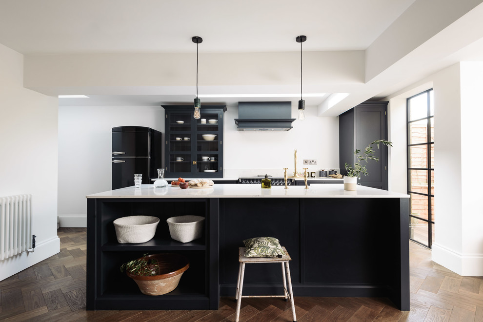 Photo of a medium sized contemporary single-wall open plan kitchen in Other with a belfast sink, shaker cabinets, blue cabinets, composite countertops, blue splashback, black appliances, medium hardwood flooring and an island.