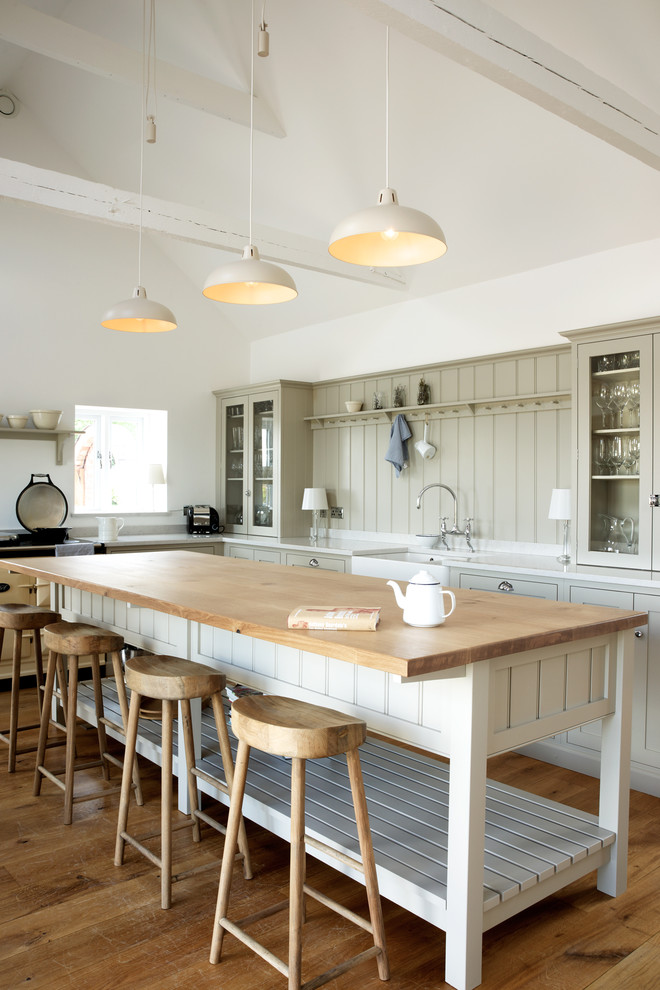 Foto de cocinas en L de estilo de casa de campo con fregadero sobremueble, puertas de armario verdes, suelo de madera en tonos medios, una isla y barras de cocina