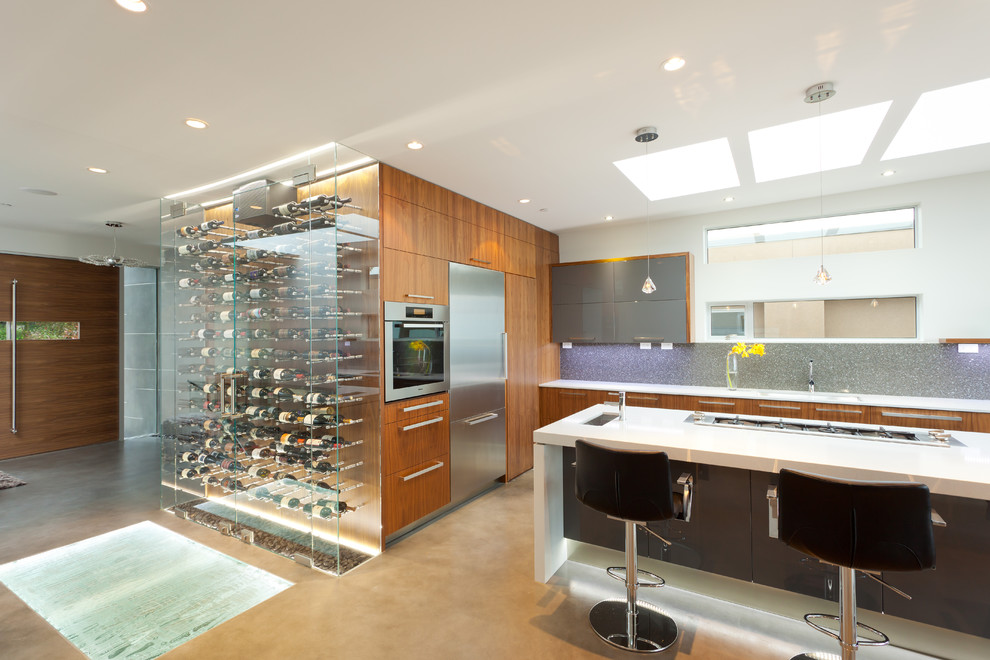 This is an example of a contemporary kitchen in Vancouver with flat-panel cabinets, grey splashback and stainless steel appliances.