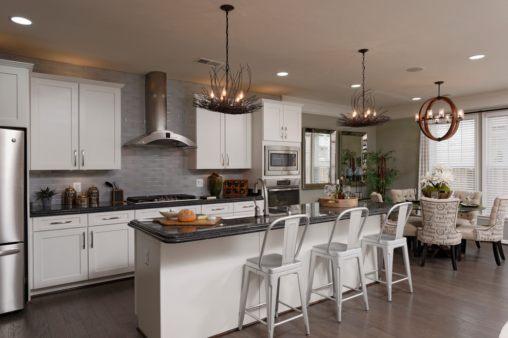 Eat-in kitchen - large modern galley dark wood floor eat-in kitchen idea in DC Metro with a farmhouse sink, shaker cabinets, white cabinets, granite countertops, gray backsplash, subway tile backsplash, stainless steel appliances and an island