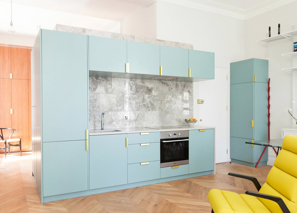 This is an example of a medium sized contemporary single-wall open plan kitchen in London with a submerged sink, flat-panel cabinets, stone tiled splashback and no island.