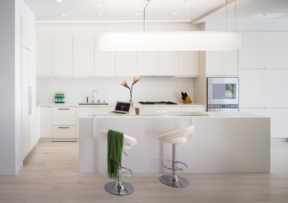 Moderne Küche in L-Form mit Unterbauwaschbecken, flächenbündigen Schrankfronten, weißen Schränken, Küchengeräten aus Edelstahl, hellem Holzboden und Kücheninsel in San Francisco