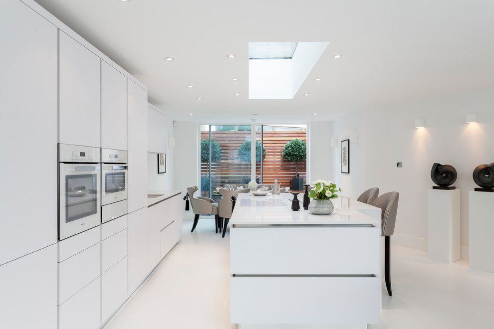 Example of a trendy kitchen design in London with flat-panel cabinets, white cabinets, white appliances and an island