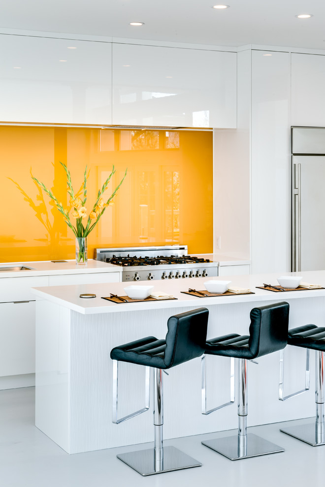 Immagine di una cucina contemporanea con ante lisce, ante bianche, paraspruzzi giallo, paraspruzzi con lastra di vetro, elettrodomestici in acciaio inossidabile e pavimento grigio