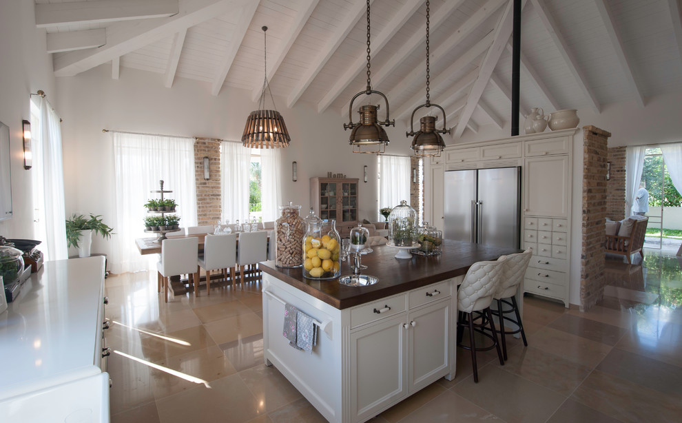 Immagine di un cucina con isola centrale classico con ante con riquadro incassato, ante beige, top in legno, elettrodomestici colorati e pavimento in travertino