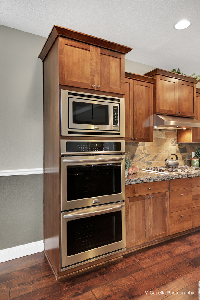 Foto di una grande cucina chic con lavello da incasso, ante in stile shaker, ante in legno bruno, top in granito, paraspruzzi marrone, elettrodomestici in acciaio inossidabile e parquet scuro