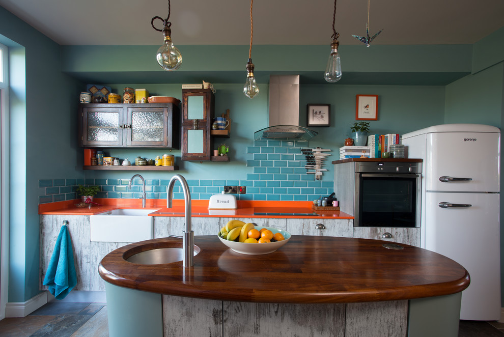 Пример оригинального дизайна: прямая кухня-гостиная среднего размера в стиле фьюжн с с полувстраиваемой мойкой (с передним бортиком), плоскими фасадами, искусственно-состаренными фасадами, синим фартуком, фартуком из керамической плитки, полом из керамогранита, островом, разноцветным полом, деревянной столешницей и белой техникой