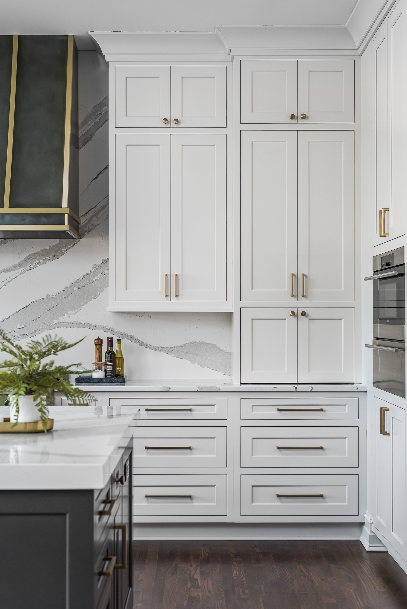 Antique brass hardware accents off white shaker cabinets topped with white  and gray marbl…