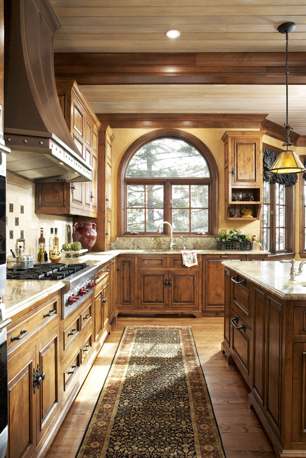 Idée de décoration pour une grande cuisine américaine tradition en L et bois brun avec un placard avec porte à panneau surélevé, un plan de travail en granite, un sol en bois brun et îlot.