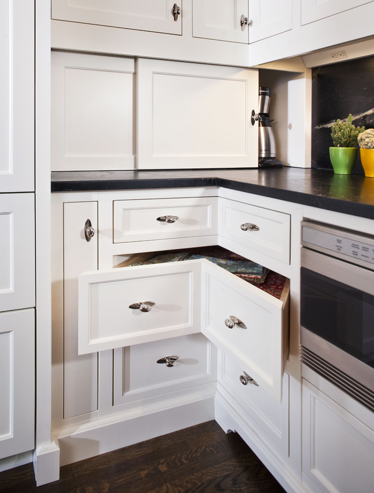 Inspiration for a large timeless l-shaped dark wood floor kitchen remodel in Minneapolis with recessed-panel cabinets, white cabinets, soapstone countertops, black backsplash, stone slab backsplash, black appliances and an island