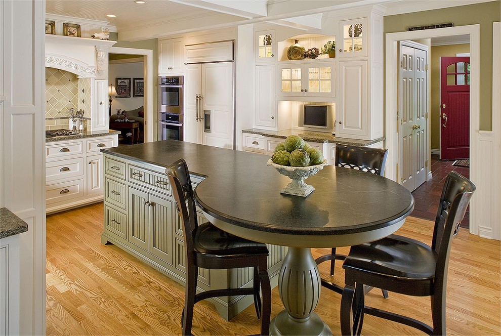 Klassisk inredning av ett mellanstort kök, med bänkskiva i täljsten, en dubbel diskho, luckor med upphöjd panel, vita skåp, ljust trägolv och en köksö