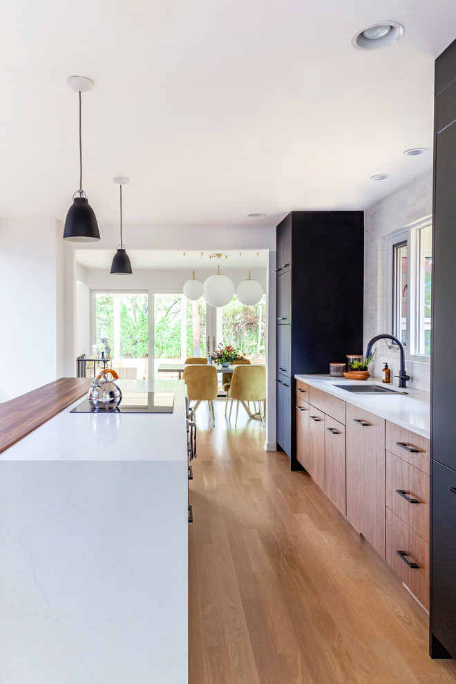 Aménagement d'une cuisine parallèle rétro en bois brun avec un sol en bois brun, îlot, un sol marron et un plan de travail multicolore.