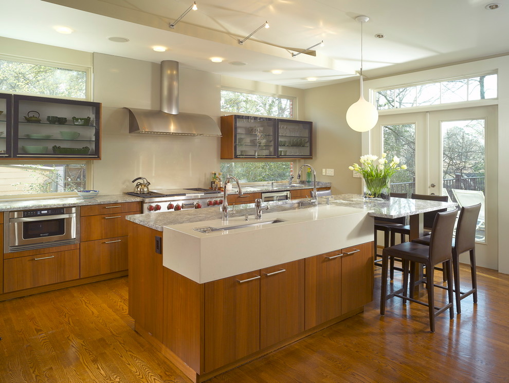 Large trendy l-shaped medium tone wood floor and brown floor eat-in kitchen photo in Atlanta with an undermount sink, flat-panel cabinets, medium tone wood cabinets, granite countertops, window backsplash, stainless steel appliances, an island and gray countertops