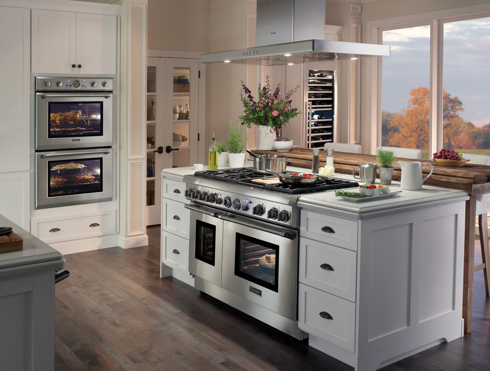 Exempel på ett mellanstort modernt kök, med vita skåp, rostfria vitvaror, mörkt trägolv och en köksö