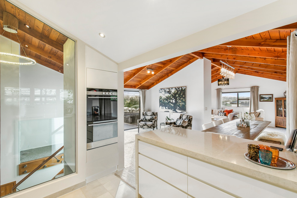 Moderne Wohnküche in U-Form mit Küchenrückwand in Weiß, Rückwand aus Metrofliesen, Porzellan-Bodenfliesen, Halbinsel, weißem Boden und weißer Arbeitsplatte in Auckland