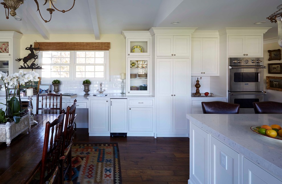 Imagen de cocina campestre, grande, con fregadero sobremueble, armarios estilo shaker, puertas de armario blancas, suelo de madera oscura, una isla, encimera de cuarcita, salpicadero blanco, salpicadero de azulejos de cerámica, electrodomésticos con paneles, suelo marrón y encimeras blancas