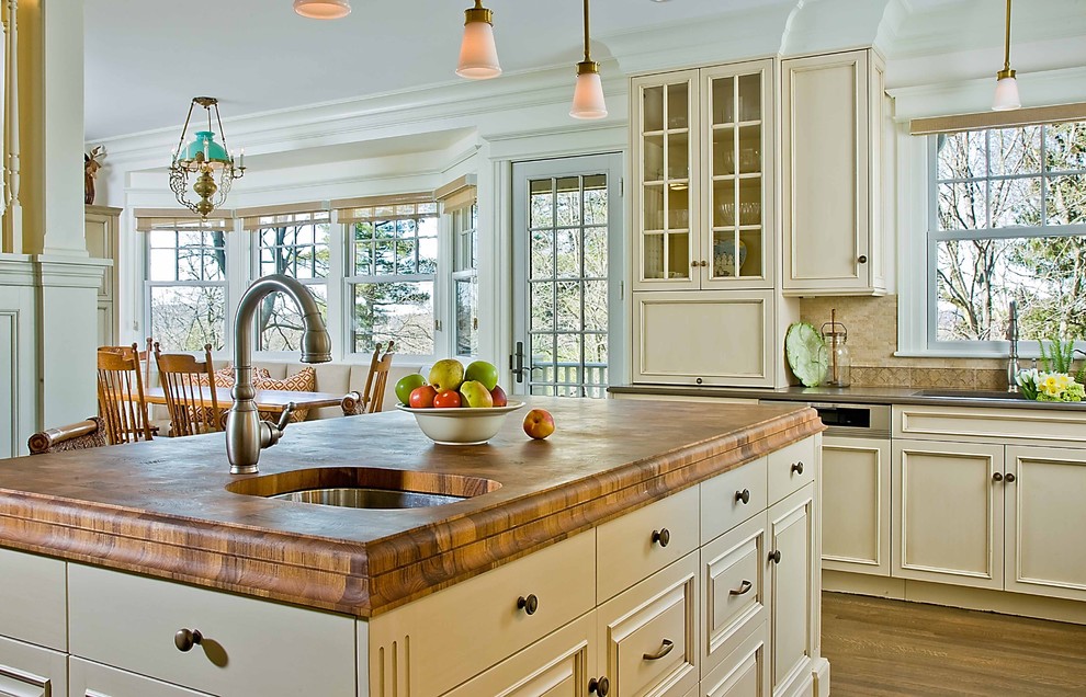 Klassische Küche mit Arbeitsplatte aus Holz, Unterbauwaschbecken und beigen Schränken in Boston