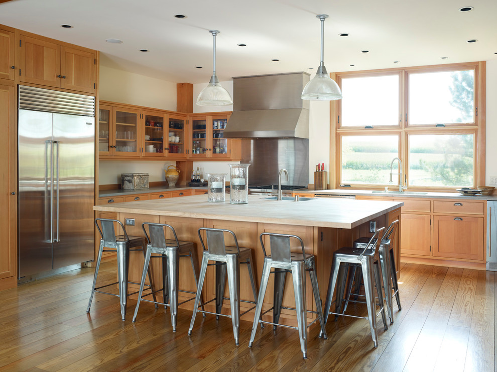 Inspiration for a farmhouse kitchen remodel in Milwaukee with glass-front cabinets, stainless steel appliances, wood countertops and medium tone wood cabinets