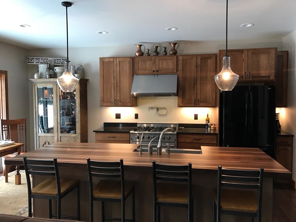 ミネアポリスにある高級な中くらいなトラディショナルスタイルのおしゃれなキッチン (シェーカースタイル扉のキャビネット、中間色木目調キャビネット、木材カウンター、シルバーの調理設備、エプロンフロントシンク、茶色い床、ラミネートの床) の写真