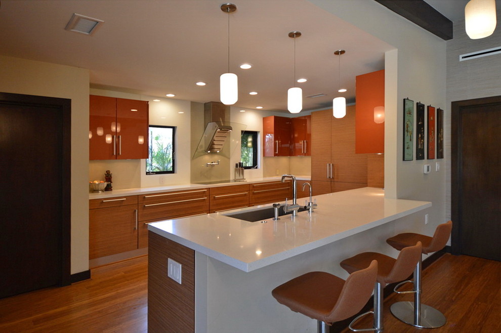 Cette image montre une grande cuisine ouverte vintage en bois brun avec un évier encastré, un placard à porte plane, plan de travail en marbre, un électroménager en acier inoxydable et un sol en bois brun.