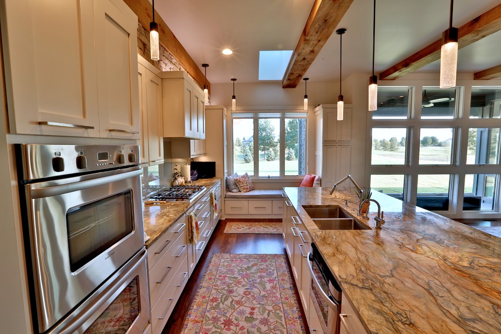 Foto på ett mellanstort 50 tals kök, med en undermonterad diskho, luckor med infälld panel, vita skåp, marmorbänkskiva, vitt stänkskydd, glaspanel som stänkskydd, rostfria vitvaror, mellanmörkt trägolv och en köksö
