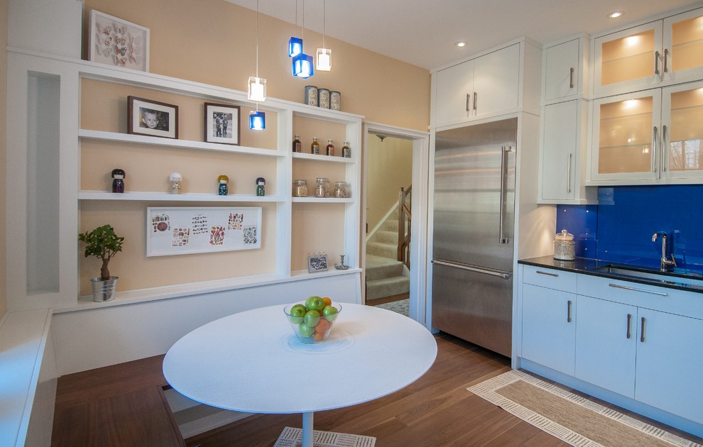 Esempio di una cucina moderna con lavello sottopiano, ante lisce, ante bianche, top in granito, paraspruzzi blu, paraspruzzi con lastra di vetro e elettrodomestici in acciaio inossidabile