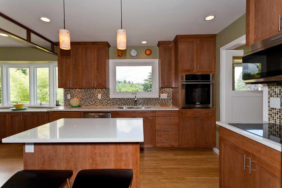 Large trendy u-shaped light wood floor and beige floor kitchen photo in Portland with a double-bowl sink, shaker cabinets, medium tone wood cabinets, quartz countertops, beige backsplash, glass tile backsplash, stainless steel appliances, an island and white countertops