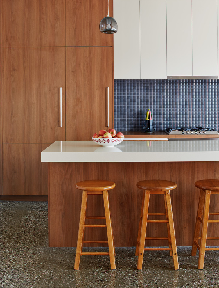 Idée de décoration pour une grande cuisine ouverte parallèle design en bois brun avec un placard à porte plane, un plan de travail en granite, une crédence bleue, une crédence en céramique, un électroménager en acier inoxydable, sol en béton ciré et un sol gris.