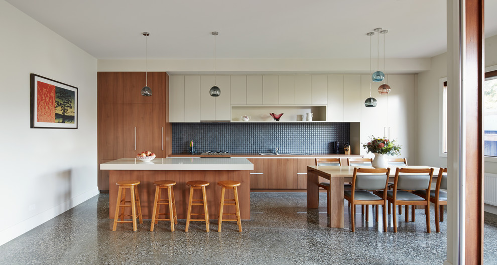 Photo of a large contemporary galley open plan kitchen in Melbourne with flat-panel cabinets, medium wood cabinets, granite worktops, blue splashback, ceramic splashback, stainless steel appliances, concrete flooring and grey floors.