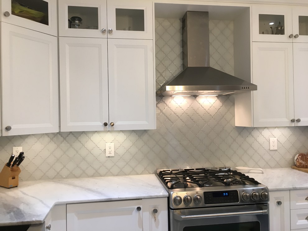 Photo of a large classic u-shaped enclosed kitchen in Toronto with a belfast sink, recessed-panel cabinets, white cabinets, quartz worktops, grey splashback, glass tiled splashback, stainless steel appliances and white worktops.