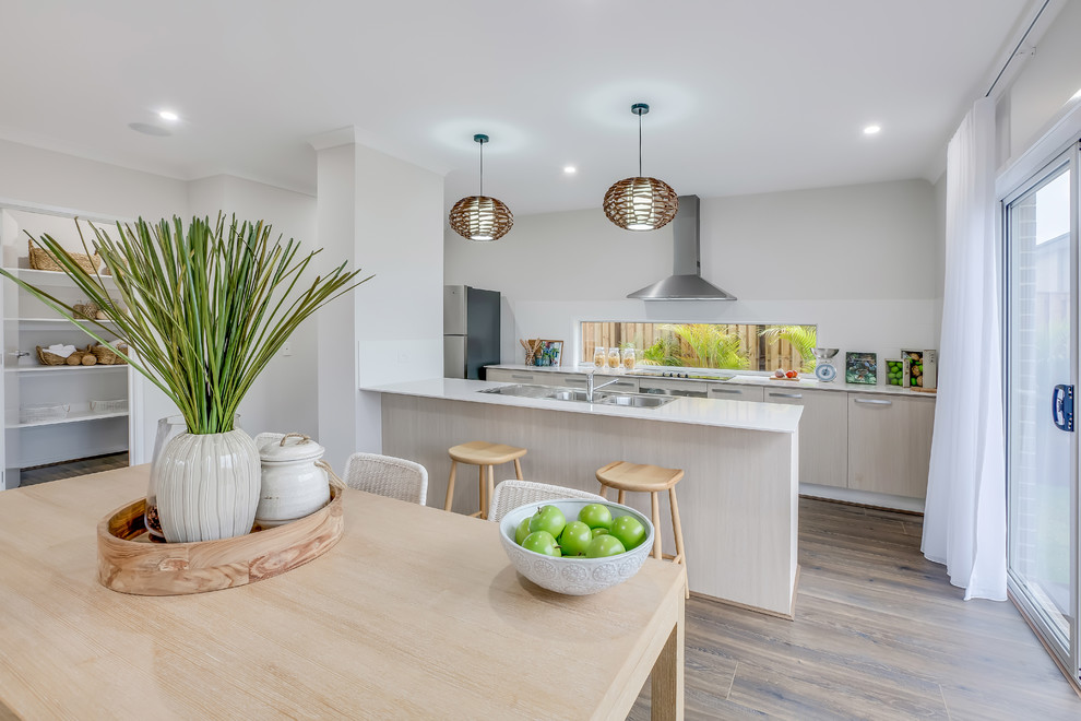 Zweizeilige Moderne Wohnküche mit Doppelwaschbecken, flächenbündigen Schrankfronten, hellen Holzschränken, Küchenrückwand in Weiß, Küchengeräten aus Edelstahl, braunem Holzboden und Halbinsel in Brisbane