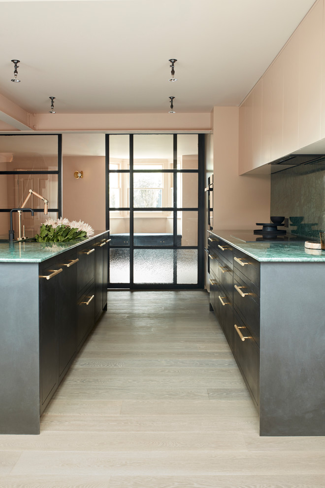 Ejemplo de cocina actual con armarios con paneles lisos, puertas de armario negras, salpicadero gris, suelo de madera clara, suelo gris y encimeras verdes
