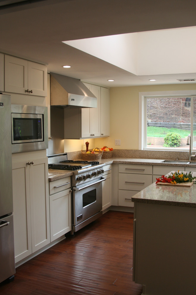 Photo of a medium sized classic u-shaped kitchen pantry in Atlanta with a submerged sink, shaker cabinets, white cabinets, stainless steel appliances, medium hardwood flooring and an island.