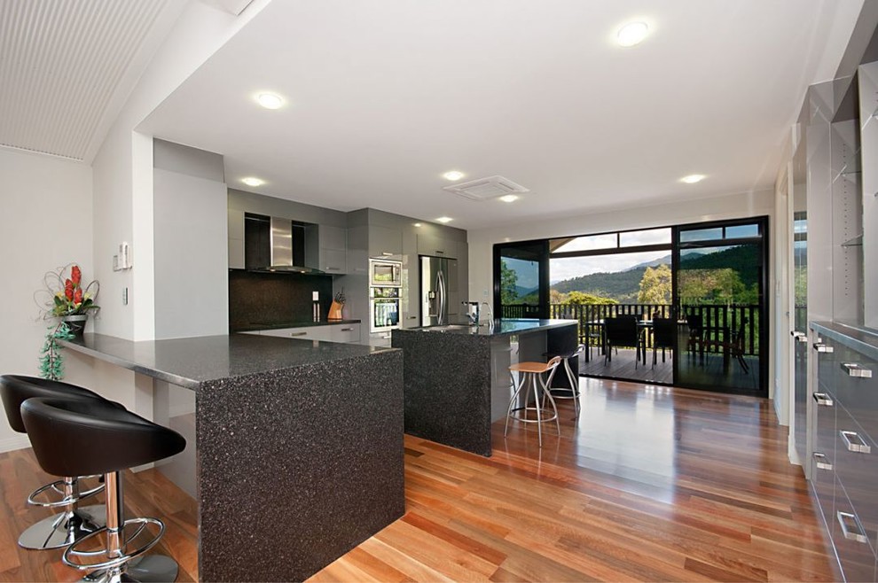 Example of a large trendy light wood floor eat-in kitchen design in Cairns with black backsplash, stainless steel appliances and an island