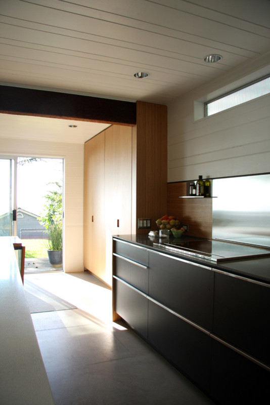 Идея дизайна: прямая кухня-гостиная среднего размера в стиле модернизм с врезной мойкой, плоскими фасадами, светлыми деревянными фасадами, техникой из нержавеющей стали, бетонным полом, островом и серым полом