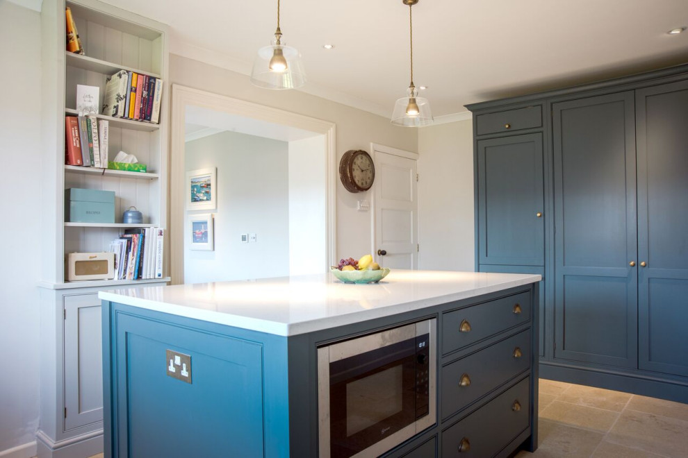 Inspiration for a large traditional u-shaped kitchen/diner in Gloucestershire with a double-bowl sink, shaker cabinets, blue cabinets, granite worktops, white splashback, glass sheet splashback, stainless steel appliances, travertine flooring, an island, beige floors and white worktops.