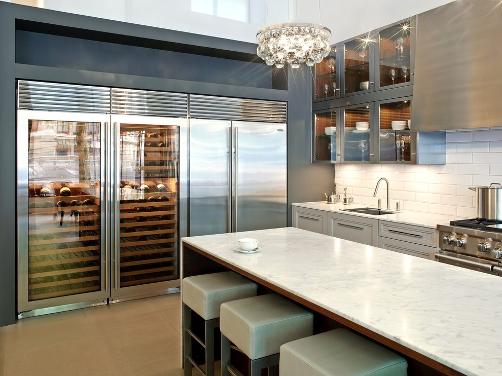 Design ideas for a contemporary galley kitchen/diner in London with a submerged sink, beaded cabinets, grey cabinets, marble worktops, white splashback, metro tiled splashback, stainless steel appliances and a breakfast bar.