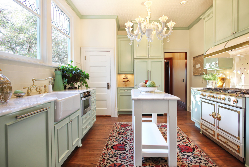 Victorian u-shaped enclosed kitchen in Portland with a belfast sink, green cabinets, recessed-panel cabinets, engineered stone countertops, beige splashback, ceramic splashback, medium hardwood flooring and an island.