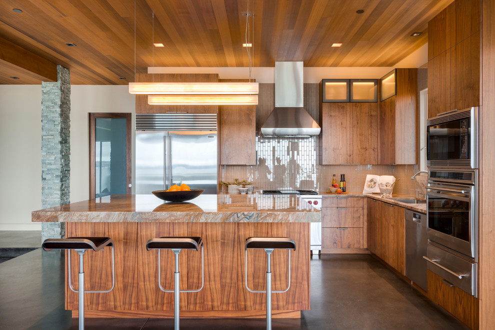 Exemple d'une cuisine tendance en L et bois brun avec un évier encastré, un placard à porte plane, une crédence beige, îlot, un plan de travail en granite et sol en béton ciré.