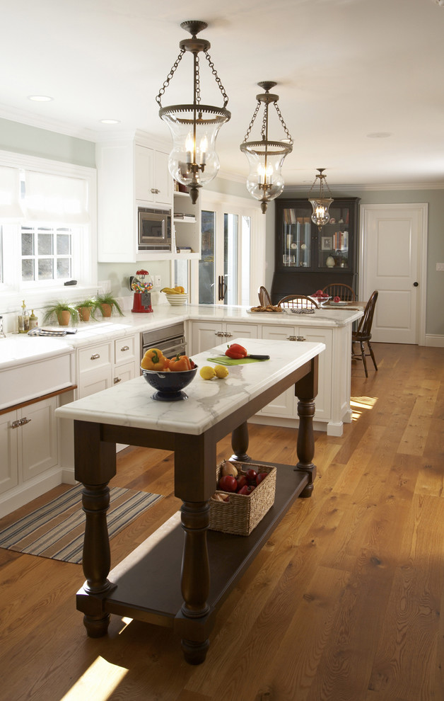 Eat-in kitchen - mid-sized traditional l-shaped medium tone wood floor eat-in kitchen idea in San Francisco with white cabinets, marble countertops, stainless steel appliances, white backsplash, ceramic backsplash, an island, a farmhouse sink and shaker cabinets