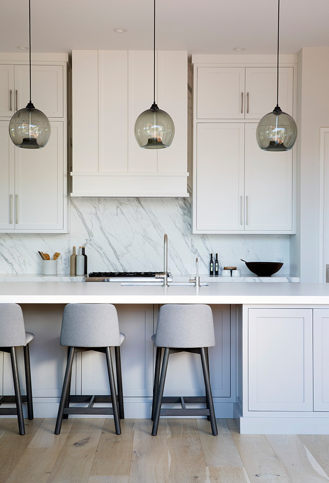 Inspiration for a large transitional l-shaped light wood floor and beige floor eat-in kitchen remodel in San Francisco with an undermount sink, shaker cabinets, white cabinets, soapstone countertops, white backsplash, stone slab backsplash, paneled appliances, an island and white countertops