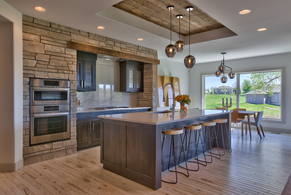 Photo of a large traditional u-shaped kitchen/diner in Omaha with a single-bowl sink, recessed-panel cabinets, dark wood cabinets, engineered stone countertops, white splashback, ceramic splashback, stainless steel appliances, ceramic flooring and an island.