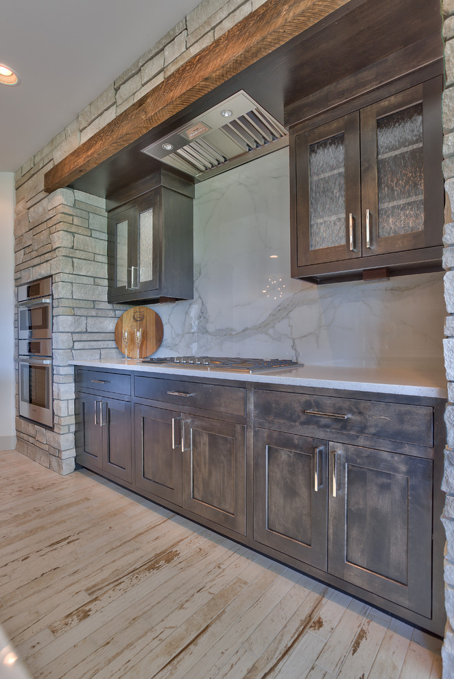 Inspiration for a medium sized rustic u-shaped kitchen/diner in Omaha with a single-bowl sink, recessed-panel cabinets, dark wood cabinets, engineered stone countertops, white splashback, ceramic splashback, stainless steel appliances, ceramic flooring and an island.