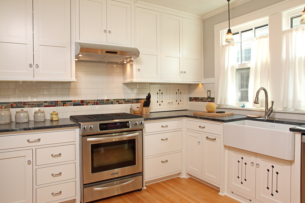 Classic enclosed kitchen in Minneapolis with a belfast sink, shaker cabinets, white cabinets, multi-coloured splashback and stainless steel appliances.