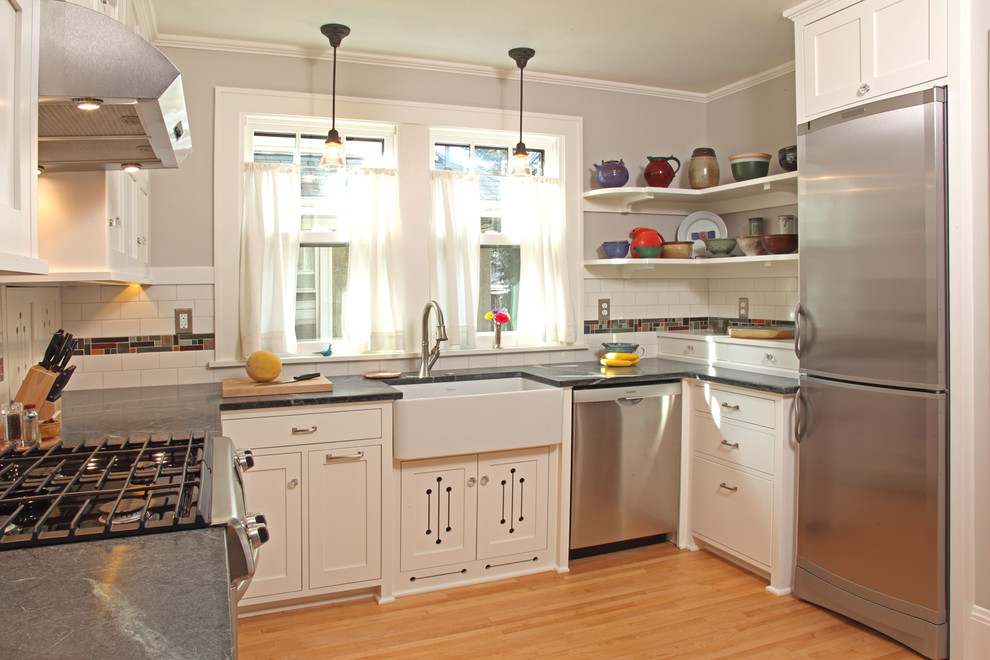 На фото: п-образная, отдельная кухня в классическом стиле с с полувстраиваемой мойкой (с передним бортиком), фасадами в стиле шейкер, белыми фасадами, разноцветным фартуком и техникой из нержавеющей стали