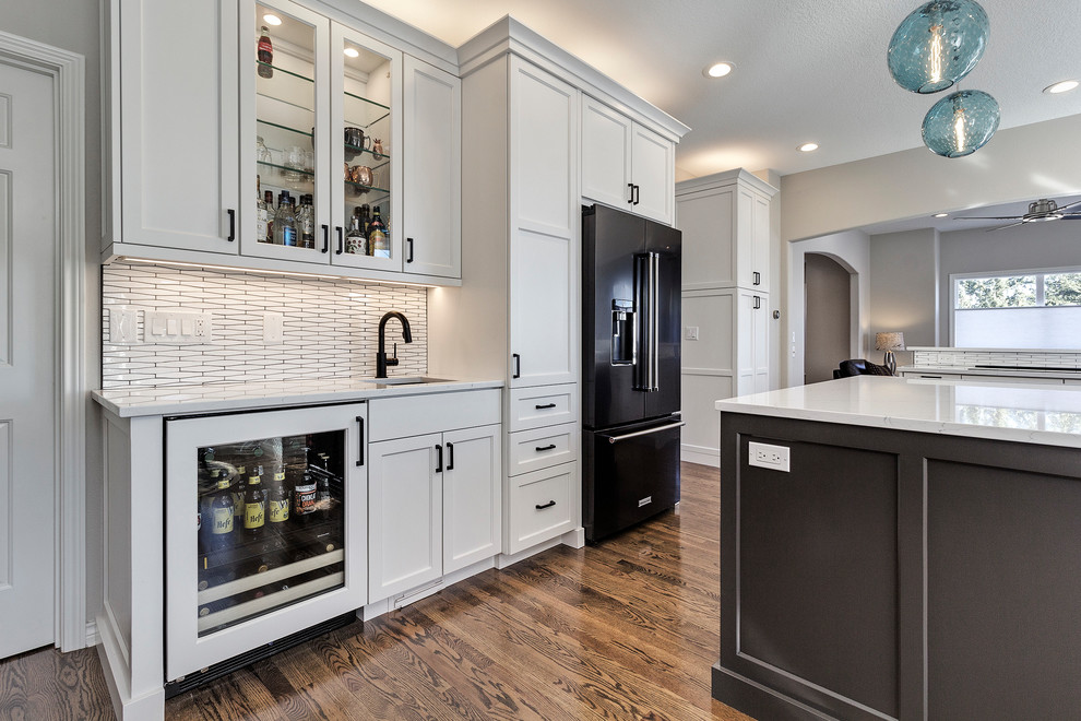 Example of a mid-sized minimalist u-shaped dark wood floor and brown floor eat-in kitchen design in Portland with an undermount sink, shaker cabinets, gray cabinets, quartzite countertops, white backsplash, mosaic tile backsplash, black appliances and an island