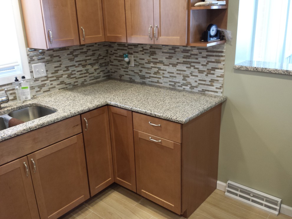 Example of a minimalist u-shaped eat-in kitchen design in Cedar Rapids with an undermount sink, shaker cabinets, medium tone wood cabinets, granite countertops, multicolored backsplash, stone tile backsplash and stainless steel appliances
