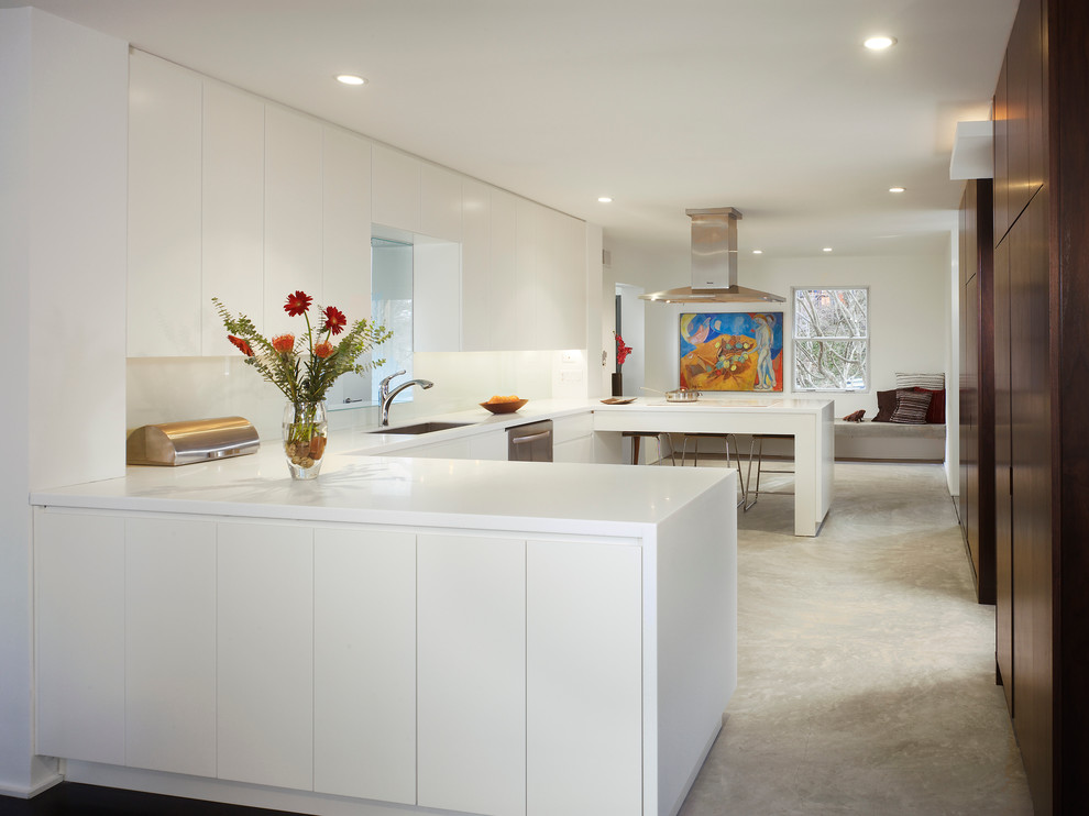 Eat-in kitchen - large modern u-shaped concrete floor eat-in kitchen idea in DC Metro with an undermount sink, flat-panel cabinets, white cabinets, solid surface countertops, white backsplash, glass sheet backsplash, stainless steel appliances and a peninsula