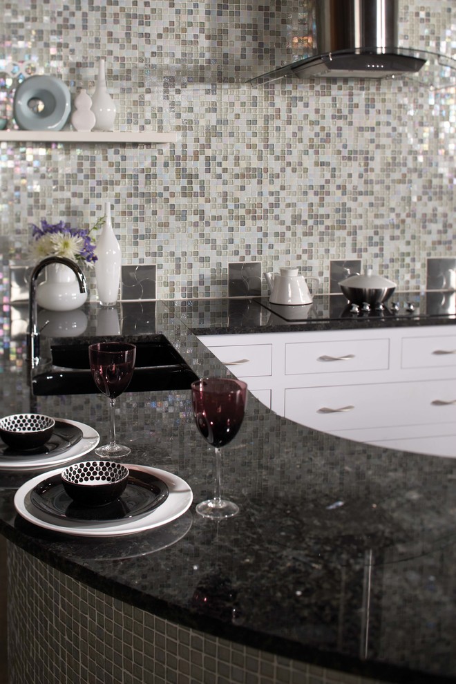 На фото: прямая кухня среднего размера в стиле модернизм с кладовкой, накладной мойкой, плоскими фасадами, белыми фасадами, столешницей из оникса, разноцветным фартуком, фартуком из плитки мозаики и черной техникой с