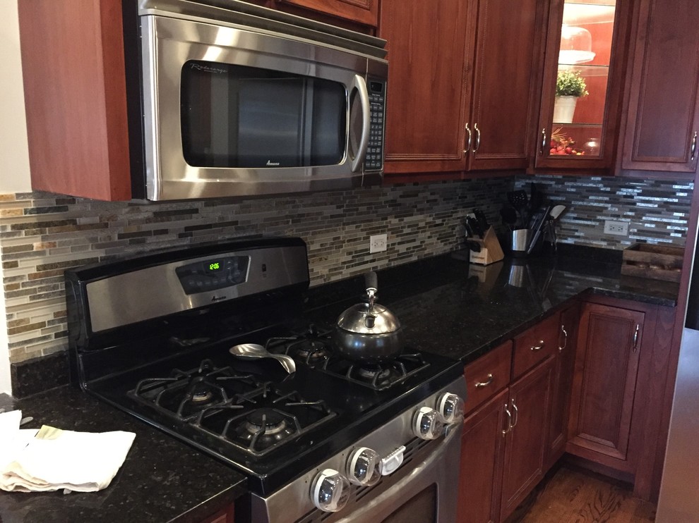 Immagine di una cucina minimalista con ante con riquadro incassato, ante marroni, top in onice, paraspruzzi grigio, paraspruzzi con piastrelle di vetro e elettrodomestici in acciaio inossidabile